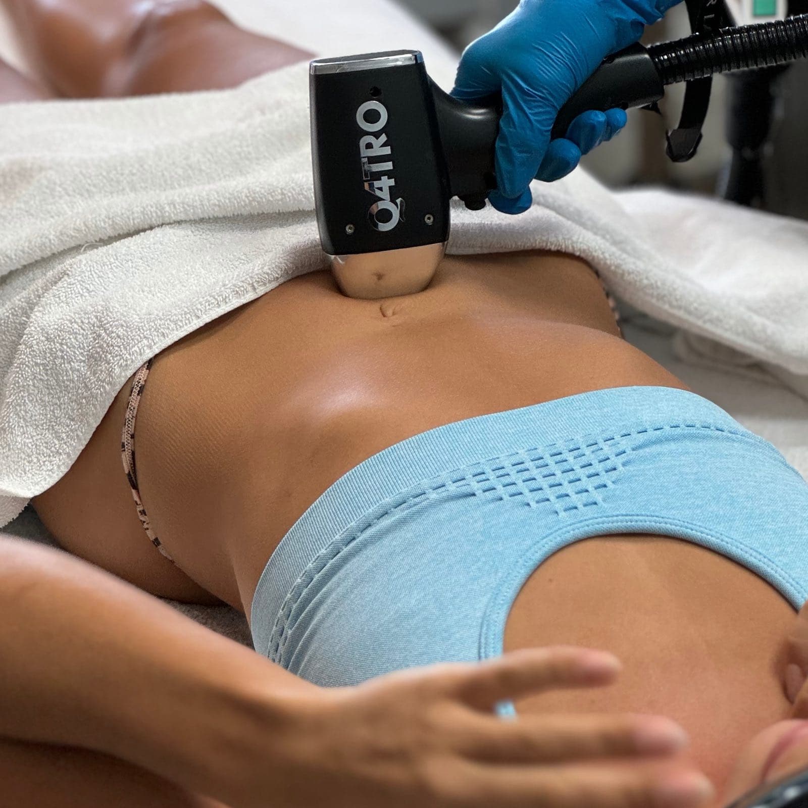 Manípulo Q4TRO sobre el abdomen bajo, junto a la línea del bikini, durante una sesión de depilación láser — Bodyfree Panamá